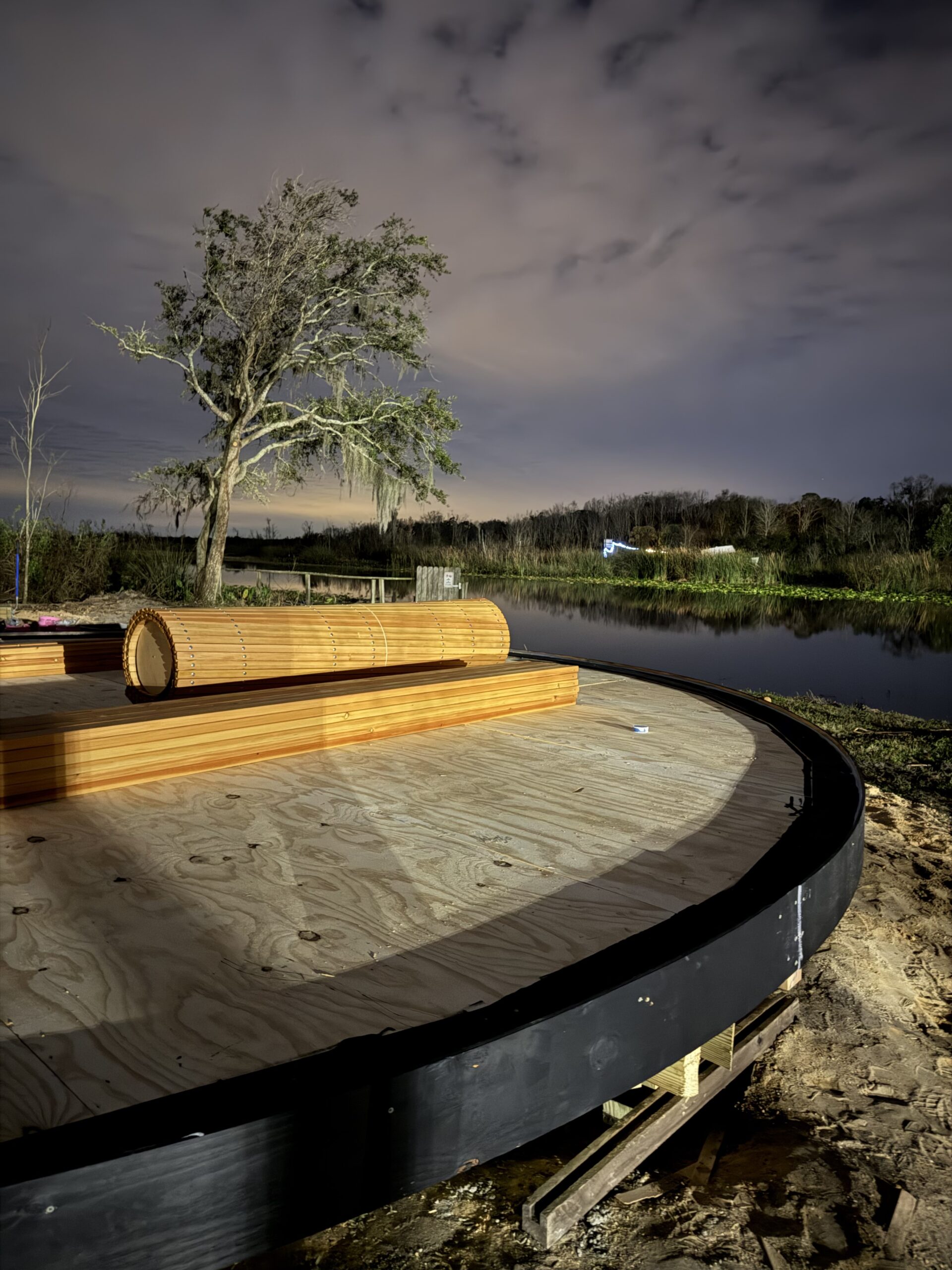 Round wood platform under construction beside a waterfront site